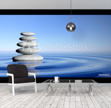 Picture of Zen stones stack from large to small in water with circular waves and blue sky